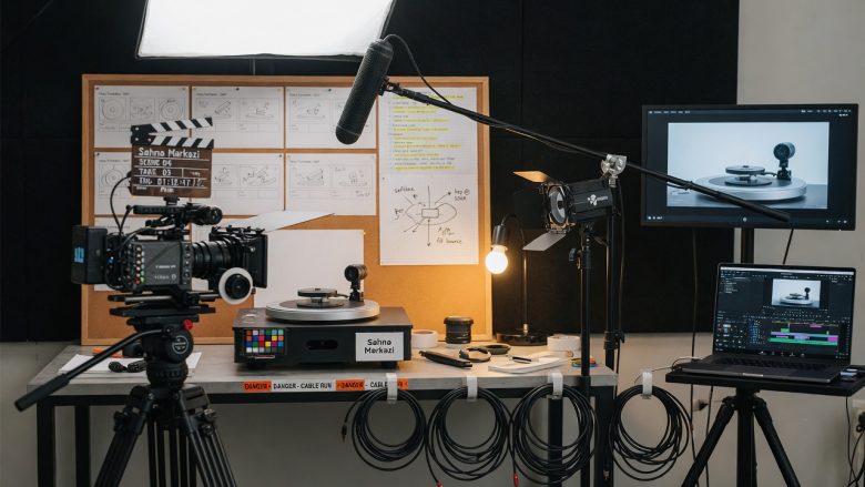 Photographic top-down flat-lay of Səhnə Mərkəzi advertising production toolkit on a dark matte table: